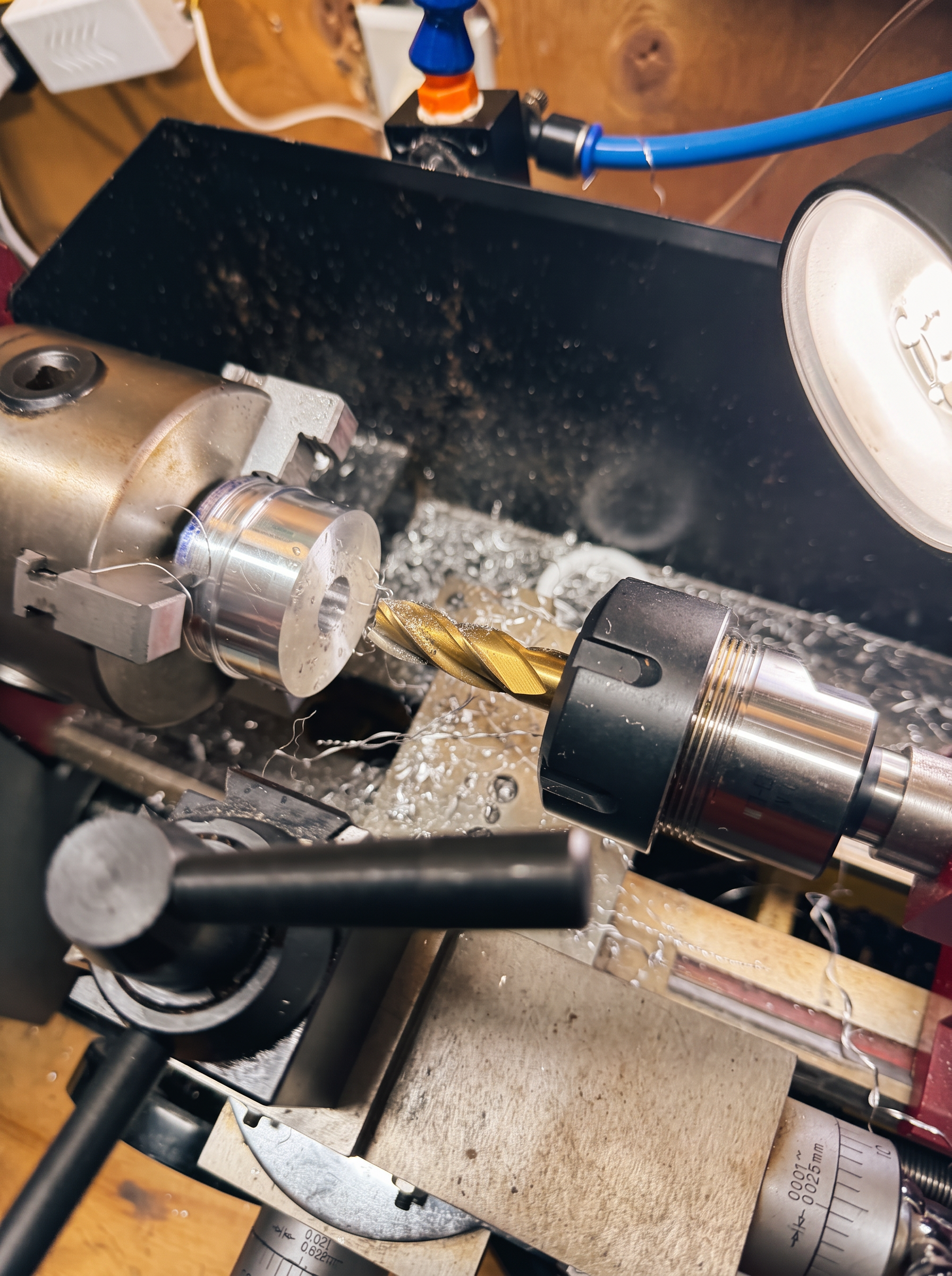 A component being drilled on the lathe, swarf gathered around the chuck
