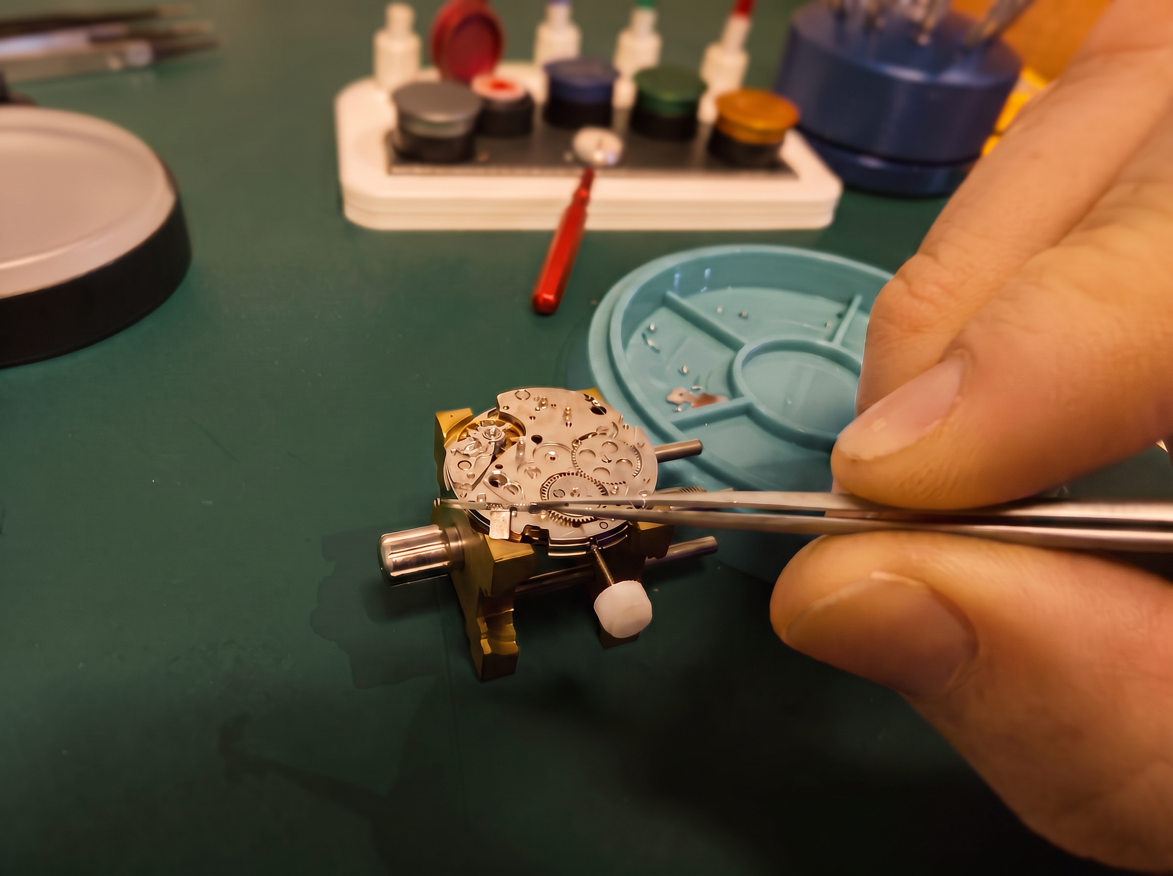 Hands adjusting a mechanical watch movement with tweezers at the Linn & North bench
